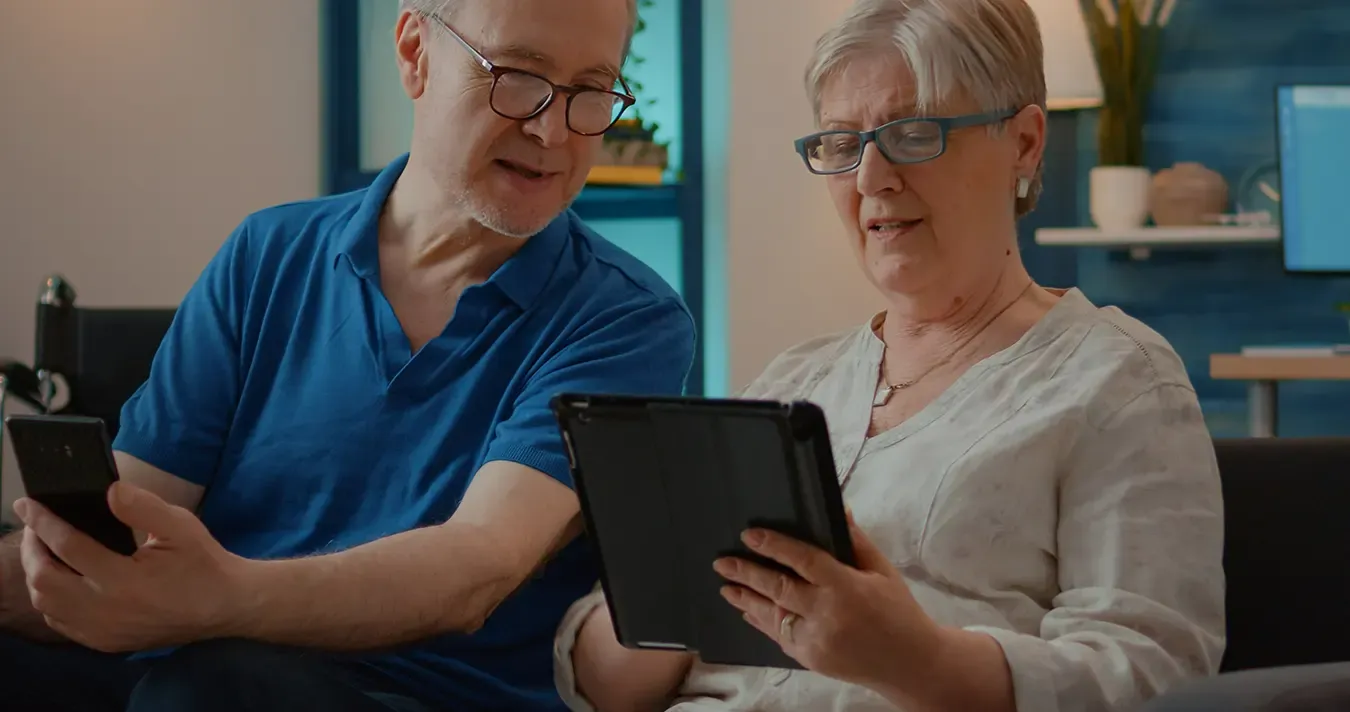 Image of two elderly people using cell phones and tablets